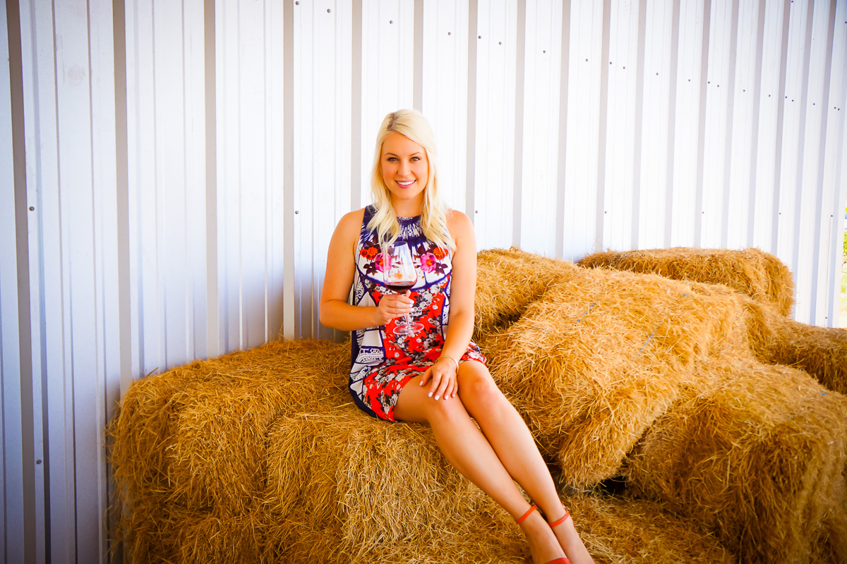 woman sitting on a stack of hay in Hilmy Cellars one of the Wineries in Fredericksburg