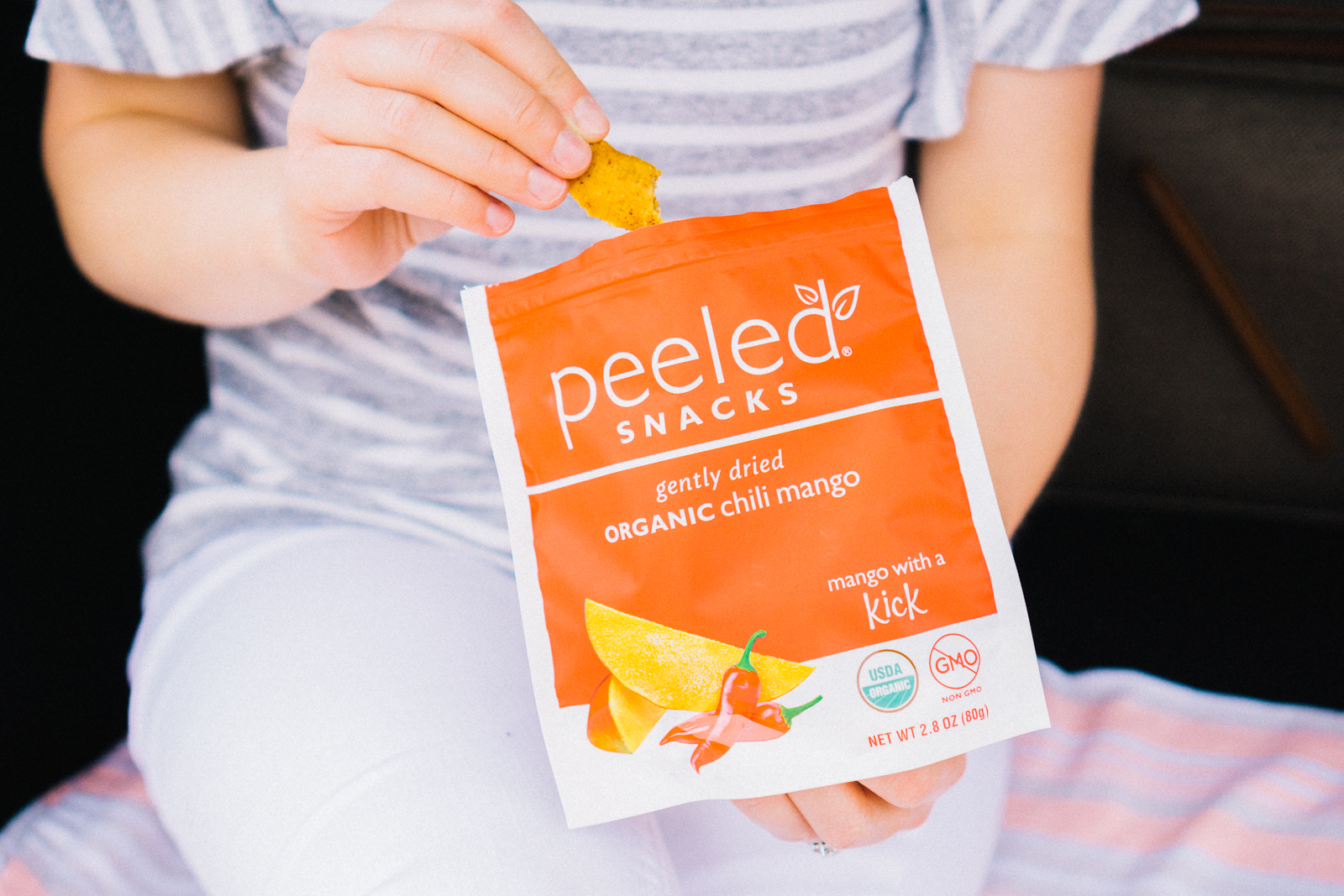 person eating a pack of peeled snacks in organic chill mango